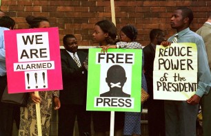 AP99021074:INTERNATIONAL:POLITICS:MEDIA:10FEB99 - Demonstrators protest outside the Harare Magistrate's court where four Zimbabwean journalists were due to be charged with publishing false information, Tuesday, February 9, 1999. The four journalists were arrested Monday and will face charges in connection with a story published in the Zimbabwe Mirror newspaper last October, which alleged that a Zimbabwean soldier's head had been returned from the Congo without its body. (AP PHOTO/Rob Cooper)