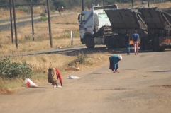 Mothers captured at GMB Bulawayo Depot picking maize grains dropping from a moving truck. Pic Chris Tabvura